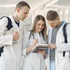 Trzech studentów medycyny w kitlach przegląda książki.